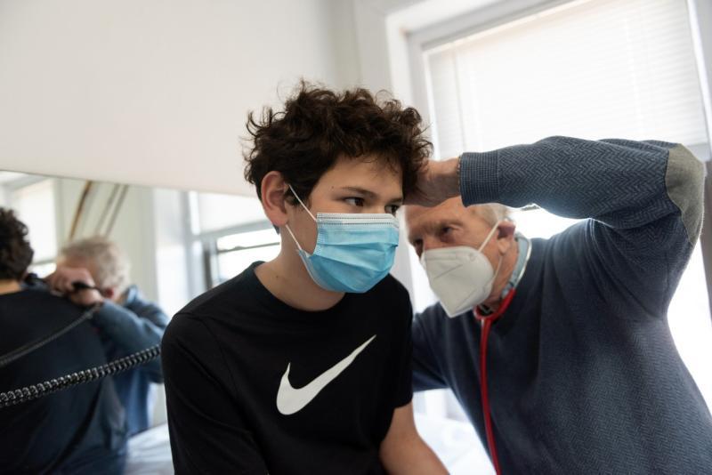 a boy wearing a mask getting his ear examined by a man